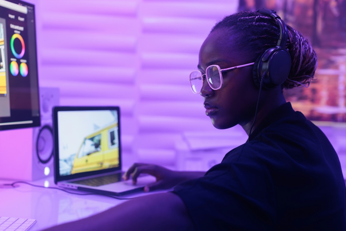 A creator editing a video at a desk in a neon-lit studio